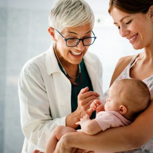 Mother holding baby for pediatrician doctor to examine Membresía Mamá integral
